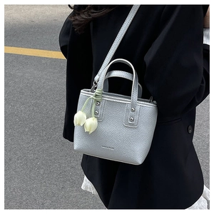 Silver litchi leather mini bucket bag with tulip charm shown in outdoor setting