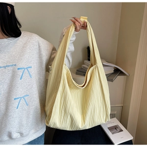 Detail of light yellow textured tote bag showing pleated fabric and large capacity