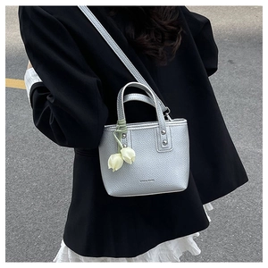 Close-up of silver metallic mini bucket bag with a white tulip flower pendant charm