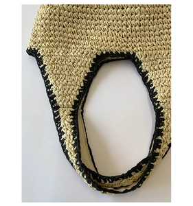 Detailed close-up showing the handwoven straw texture and black crochet edge of the beach tote