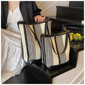 Set of large and small striped canvas tote bags with black leather trim and handles