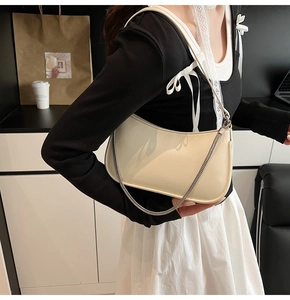 Chic off-white hobo bag with silver chain detail worn by a model in urban setting