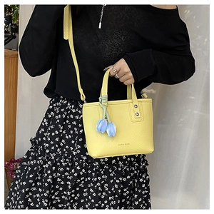Detail of yellow lychee texture tote bag with a tulip pendant shown on model
