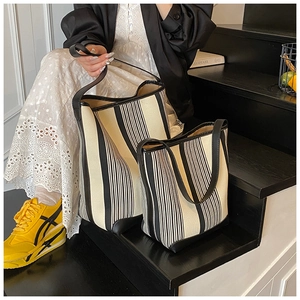 Detailed set of canvas striped tote bags with leather trim in two sizes on stairs