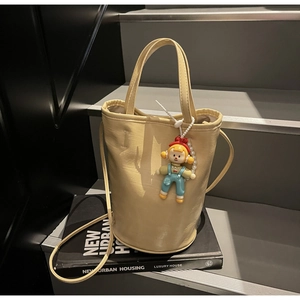 Détail du sac seau en cuir PU jaune crème avec charm de dessin animé et fine bandoulière