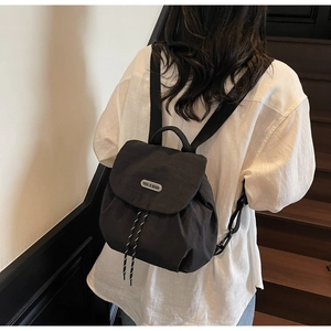 Detail of waterproof nylon backpack with drawstring closure and silver brand plaque