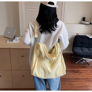 Detail of the yellow tote bag featuring a pleated texture and a wide shoulder strap