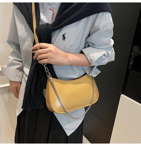 Close-up of bright yellow crescent crossbody bag with silver chain and smooth leather texture