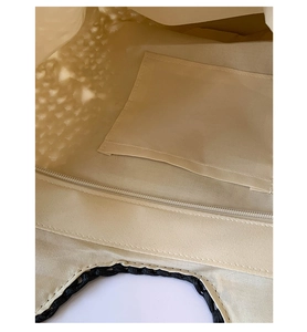 Close-up of woven straw tote bag interior showing beige fabric lining and zipper closure