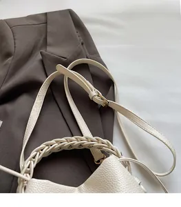 Detail of white lychee leather bucket bag with woven handle and adjustable strap