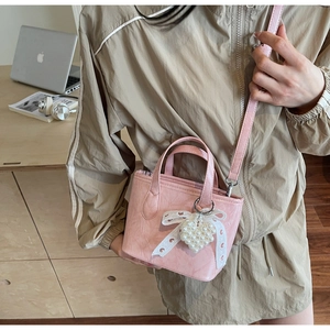 Borsa a secchiello rosa con fiocco di pizzo e cuore di perle in un ambiente accogliente