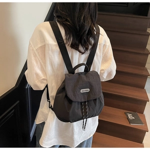 Rear view of a black nylon drawstring backpack featuring a silver brand logo on the flap
