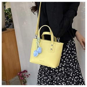 Bright yellow pebbled leather bucket bag with a blue tulip charm decoration