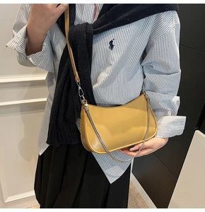 Detail of yellow hobo bag with silver chain and thin strap on person shoulder