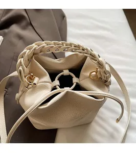 Detail of lychee pattern beige bucket bag with metal ring closure and woven handle