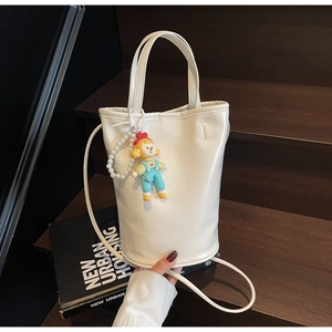 Détail du sac seau blanc crème avec motif crocodile, chaîne en perles et charme poupée