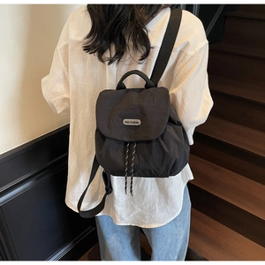 Detail of black nylon mini backpack featuring drawstring closure and metallic logo