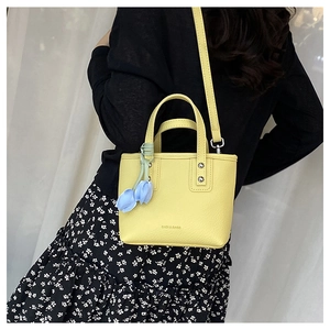 Detail of yellow bucket bag with lychee texture and blue tulip charm decor