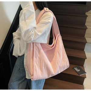 Pink pleated hobo bag worn by model on shoulder showing large capacity and soft texture