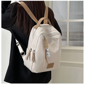 Detail of waterproof nylon backpack with brown leather straps and cute bear pendant
