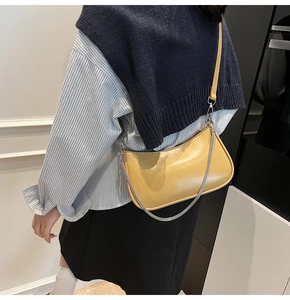Model wearing a bright yellow faux leather shoulder bag with a silver chain accent