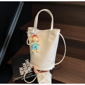 Vue détaillée du sac seau blanc avec texture craquelée et breloque poupée mignonne