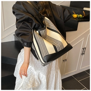 Lifestyle shot of large striped canvas tote bag with black leather trim on model