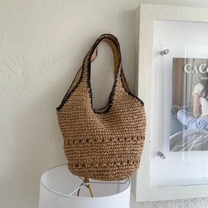 Detailed view of the hollow woven pattern on a light brown straw shoulder tote bag