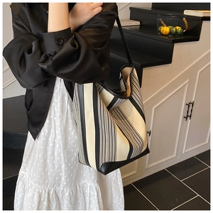 Detail of black and white striped canvas tote with leather straps in home setting