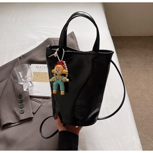 Détail du sac seau noir brillant avec charme et livre d'art Matisse sur un lit