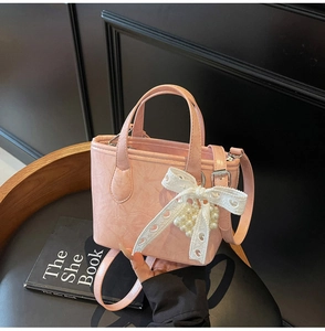 Dettaglio della borsa a secchiello in pelle PU rosa con fiocco in pizzo e perline