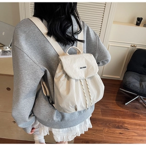 Vista posteriore dettagliata di uno zaino in nylon beige con coulisse indossato dal modello