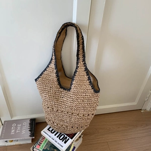 Macro detail of hand-woven straw tote bag with black trim and spacious fabric lining