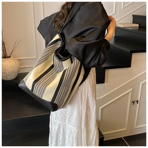 Detail of the large striped canvas tote bag showing its durable shoulder strap on a model