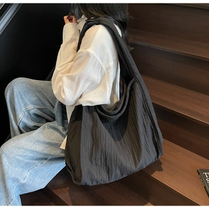 Side view of large black textured hobo bag worn by a model on stairs for daily commuting