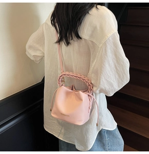 Detail of pink bucket bag with woven handle and drawstring shown in outdoor lifestyle setting
