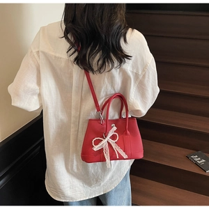 Detail of red bucket bag with lace pearl bow on stairs with white shirt