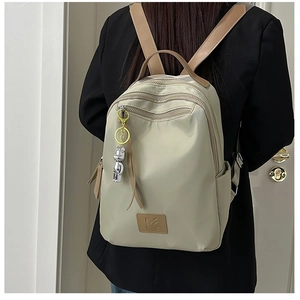 Close-up of beige waterproof nylon backpack with leather straps and bear charm