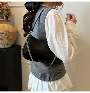Close-up of black crossbody bag with silver chain detail and sleek faux leather finish
