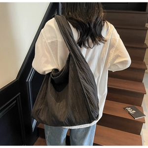 Detailed view of the black pleated nylon tote bag with texture on a model's shoulder
