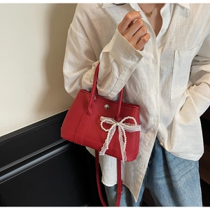 Detailed macro view of red lychee textured leather bag with pearl lace bow charm