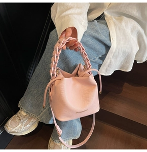 Pink bucket bag with woven handle shown with white linen shirt and denim jeans