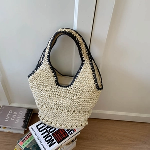 Close-up of the woven straw texture and black crochet trim on the large beach tote bag