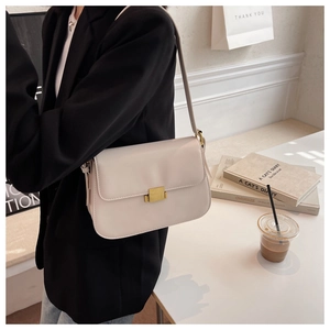 Detailed shot of cream white crossbody bag with a gold metal lock and smooth leather