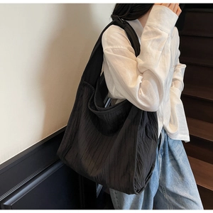 Detailed close-up of textured black oversized tote bag showing wrinkled fabric on model shoulder