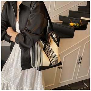 Detail of large canvas tote with black and white vertical stripes and reinforced handles