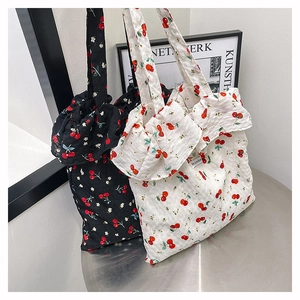 Detailed view of mesh tote bags with cherry prints in black and white styles