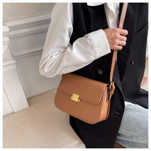 Detail of camel brown leather crossbody bag with elegant square gold metal buckle
