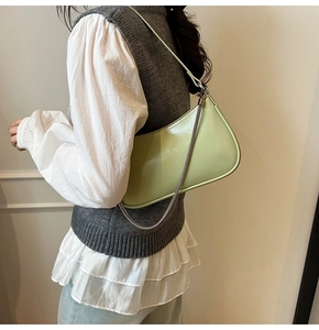 Detail of light green leather shoulder bag with fine metal chain on model