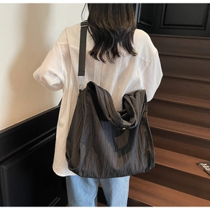 Detailed view of the dark textured pleated tote bag with adjustable strap on a model